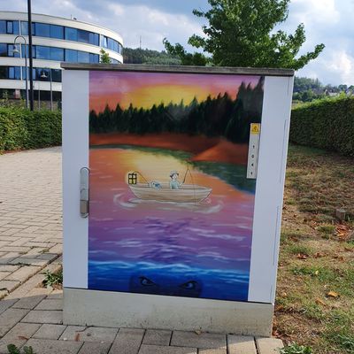Bild vergr&ouml;&szlig;ern: Stromkasten bemalt mit einem See bei Sonnenuntergang und Boot mit Angler darauf