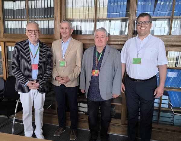 Bild vergr&ouml;&szlig;ern: Vier M�nner vor einem B�cherregal