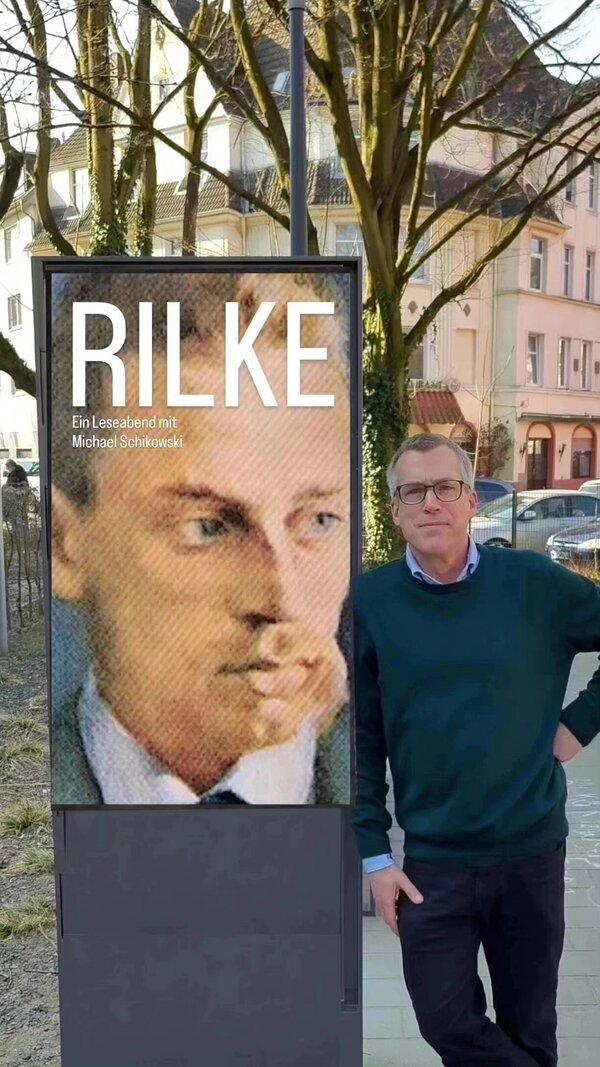 Bild vergr&ouml;&szlig;ern: Ein Mann lehnt sich an ein Werbeplakat.