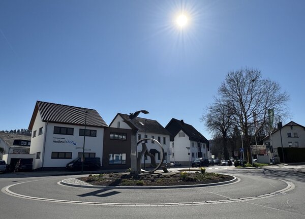 Blick auf einen Kreisverkehr mit geschwungener Stahlskulptur in der Mitte