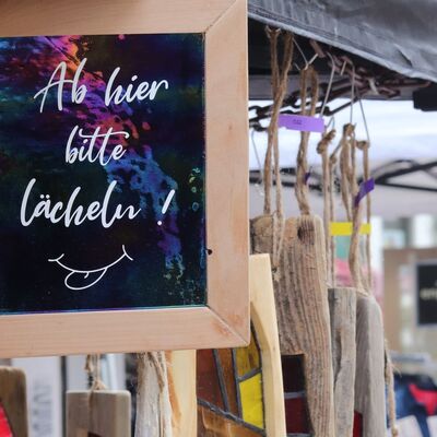 Bild vergr&ouml;&szlig;ern: Schild mit dem Text "Bitte l�cheln" an einem Verkaufsstand