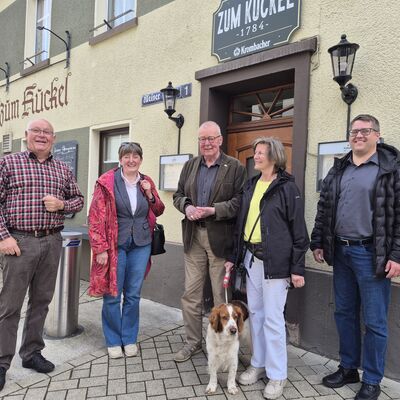 Bild vergr&ouml;&szlig;ern: F�nf Erwachsene und ein Hund vor einem Geb�ude.