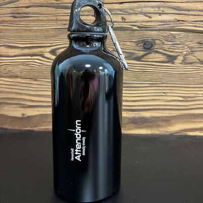 Bild vergr&ouml;&szlig;ern: Eine schwarze Trinkflasche mit dem Attendorn Logo steht vor einer Holzwand.