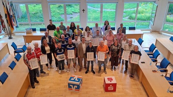 Bild vergr&ouml;&szlig;ern: Viele Menschen in einem Raum mit Urkunden.